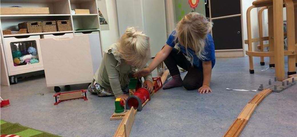 Børn leger med tog på en stue