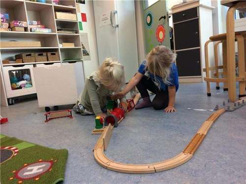 Børn leger med tog på en stue