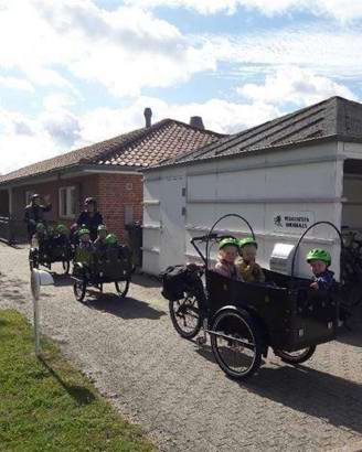 børn i ladcykler foran Vuggestuen Solsikken