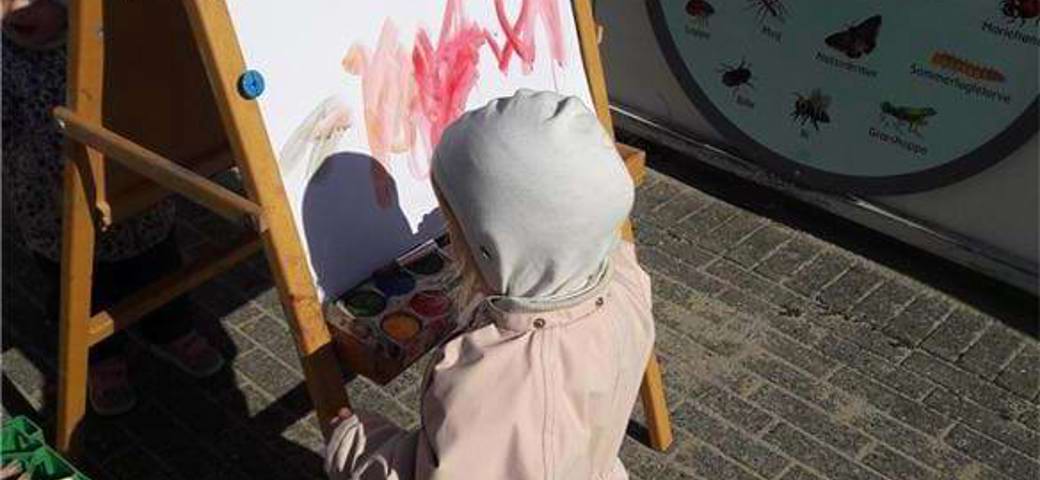 barn maler på tavle udenfor