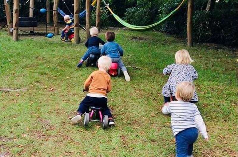 børn løber og kører på scooter på legepladsen